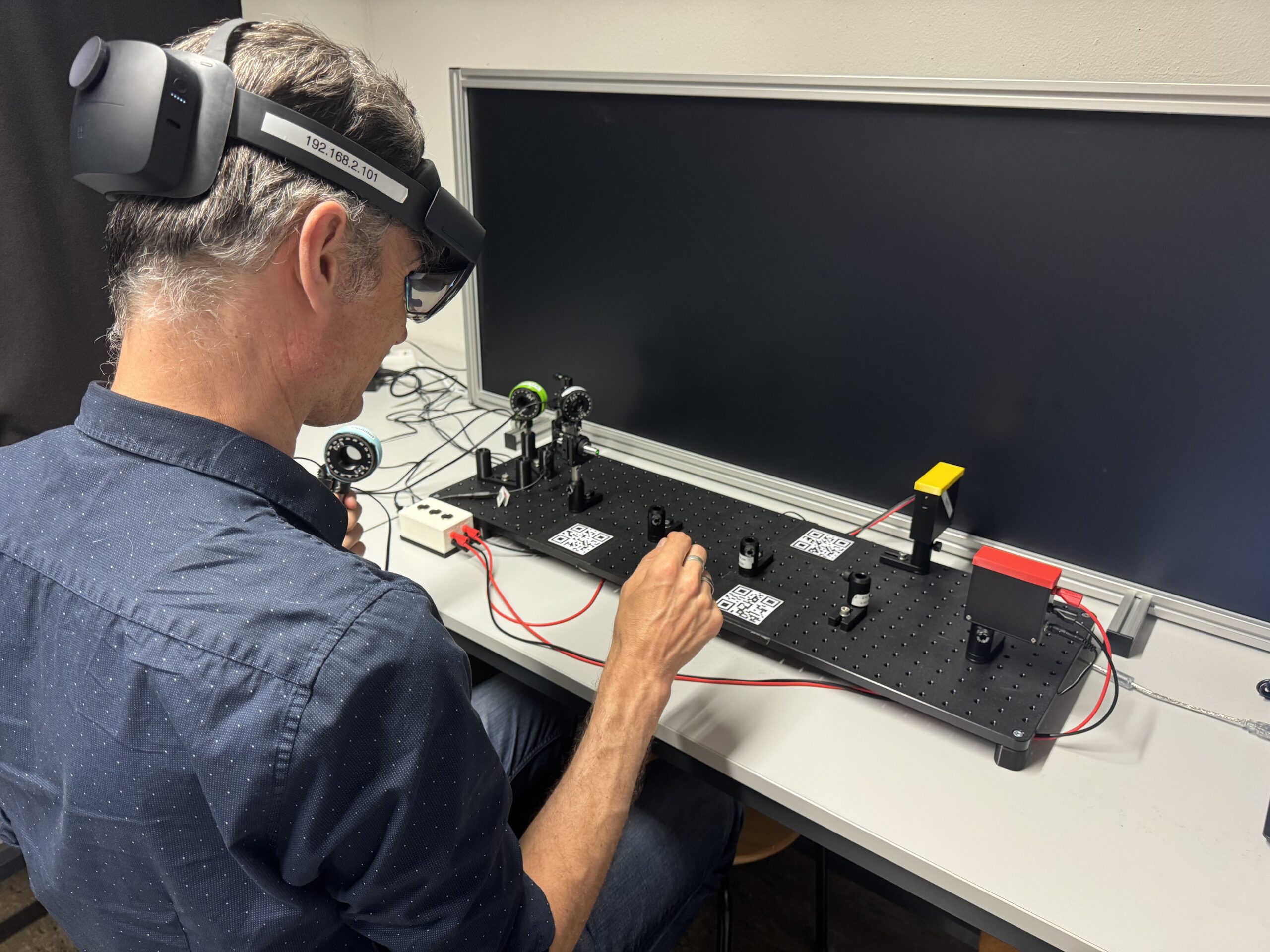 Ein Mann sitzt am Tisch und testet ein Virtual-Reaily-Gerät aus.