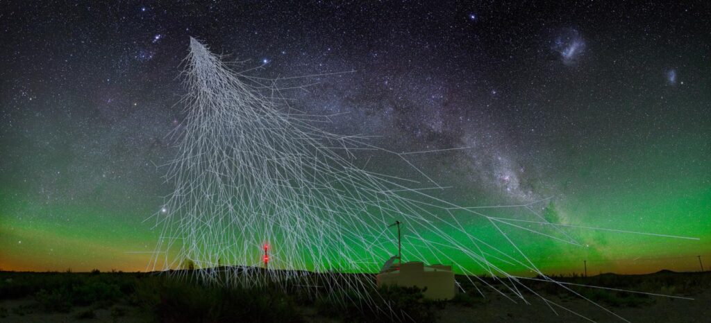 Künstlerische Darstellung eines Luftschauers über einem Teilchendetektor des Pierre-Auger-Observatoriums vor einem sternenklaren Himmel